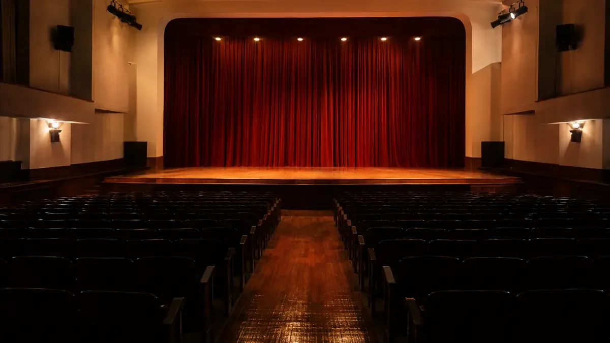 Escenario iluminado y butacas vacías de un teatro municipal genérico.